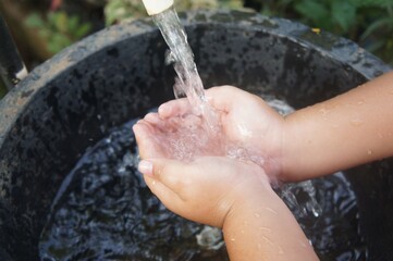 Fototapeta premium A boy washes his hands at an outdoor sink. Improving hygiene, health services, and disease prevention. The concept of hygiene, safety, and handwashing habits in children's education.