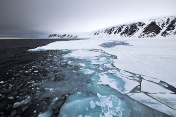 Floating ice on the ocean with mountains in the background in the arctic of Svalbard, Norway © Reto Ammann
