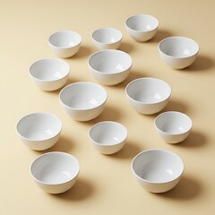 A collection of various sized white bowls arranged on a pale beige surface.