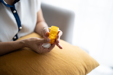 Senior Asian Woman Taking Daily Medicine, Putting Pills from Bottle in Caring Home
