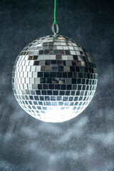 Disco ball hanging is comprised of small mirrors and has a light reflecting on it for a party effect