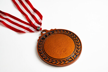 Closeup view of the bronze award medal suspended from a red and white striped ribbon isolated over...