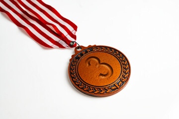Closeup view of the 3rd bronze award medal suspended from a red and white striped ribbon isolated...