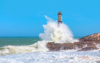 Beautiful red and white lighthouse on the rocks with strong sea wave - Namibia, Africa