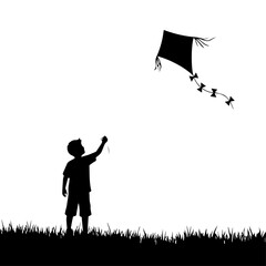 Silhouette of a boy flying a kite in a field.