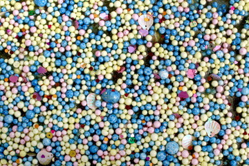 Various small multi-colored balls lie on the surface, texture.