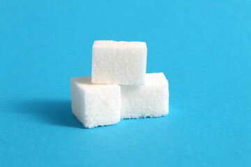 Three refined sugar squares lie on a blue background.