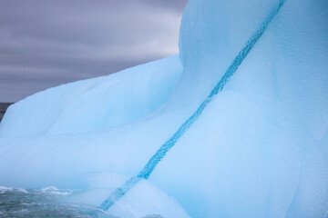 Blue crack in an iceberg from a glacier before a storm drifting in the ocean of Svalbard, Norway