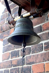 Fototapeta premium A small bell with a clapper hangs by the wall.