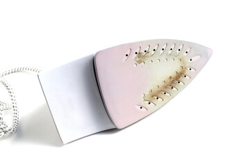 An iron with a burnt bottom is located on a white background.	