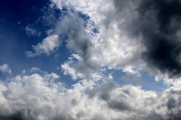 Background of blue bright sky with dark clouds.
