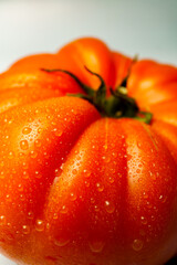 Macro photography showcasing refreshing water droplets on a vibrant orange tomato, emphasizing freshness and natural textures