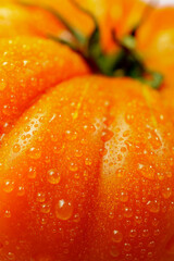 Macro photography showcasing refreshing water droplets on a vibrant orange tomato, emphasizing freshness and natural textures