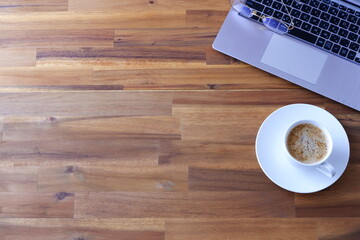 淹れたての美味しいコーヒー、カフェ・ラッテを飲みながら、ノートパソコンでデスクワークをしているイメージ
