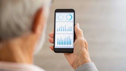 A person examines data on a smartphone, showcasing graphs and statistics, highlighting technology use in daily life.