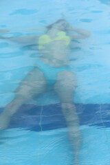 Motionless girl on the blue pool bottom appearing tragically drowned
