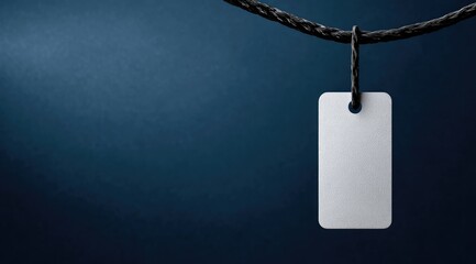 A blank rectangular tag hangs from a dark cord against a deep blue backdrop, providing ample copy space