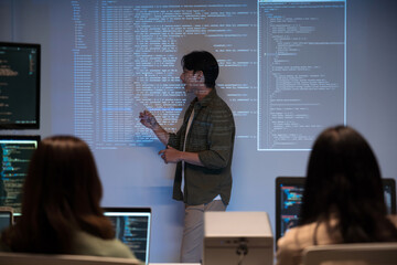 Asian man presents code using a projector during a software development meeting or coding workshop,...
