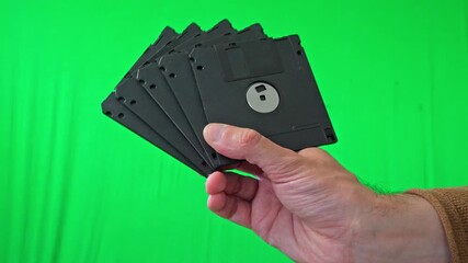 A nostalgic and technical mood is captured as a hand holds a fanned stack of classic 3.5-inch floppy disks, ready for integration into various digital or historical themes - Powered by Adobe