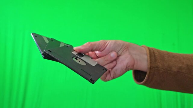 A nostalgic and technical mood is captured as a hand holds a fanned stack of classic 3.5-inch floppy disks, ready for integration into various digital or historical themes
