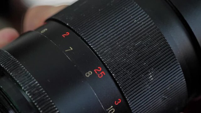 A detailed and technical mood is captured by a close-up of the aperture and focus rings on a vintage camera lens, highlighting the numerical markings and intricate design