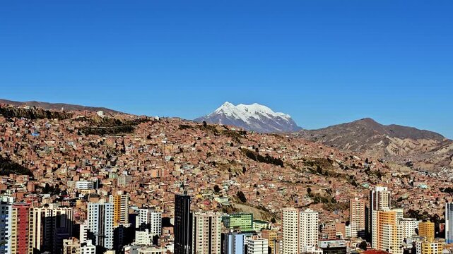 Beautiful view of La Paz city with colorful buildings and Illimani mountain in background, bright blue sky and urban mountain scenery of Bolivia.