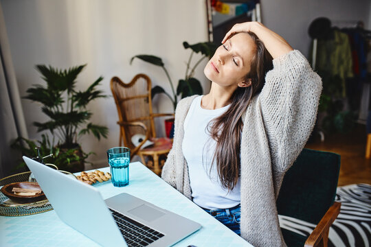 Tired freelancer with eyes closed sitting at desk