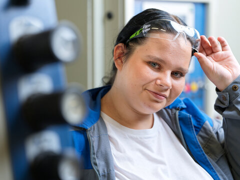 Smiling apprentice wearing protective eyeglasses at workshop