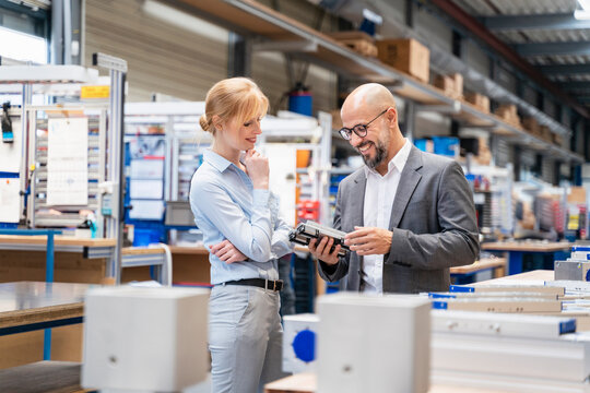 Businessman and businesswoman examining workpiece in factory
