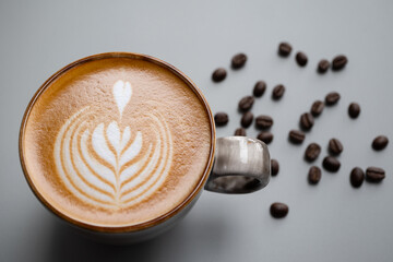 Tulip style Latte art in a ceramic cup  place on gray background  with copy space right, there are coffee beans around