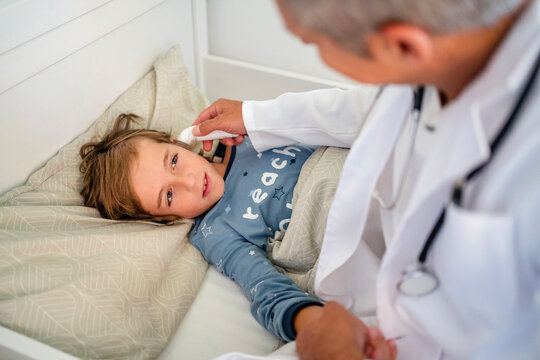 Doctor examining boy in bed at home
