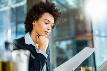Businesswoman with hand on chin reading document at office
