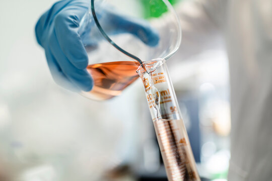Hand of scientist pouring chemical in test tube at laboratory