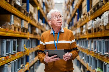 Senior man with tablet PC examining stock at warehouse