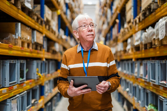 Senior man with tablet PC examining stock at warehouse
