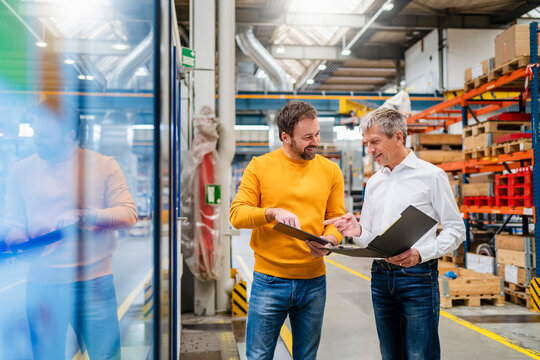 Smiling business colleagues planning in production hall at factory