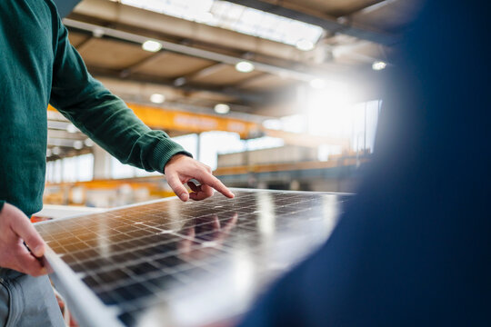 Manager touching solar panel at factory