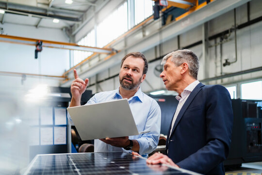 Manager pointing by businessman discussing at factory
