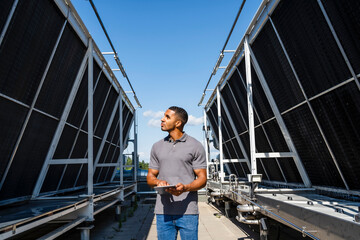Employee with digital tablet checking refrigeration installation on rooftop