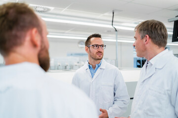 Team of competent electrical technicians in lab coats having meeting in electronics factory