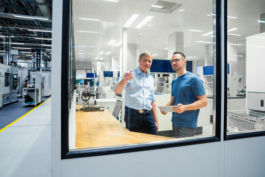 Businessman and employee with digital tablet having a discussion in a factory