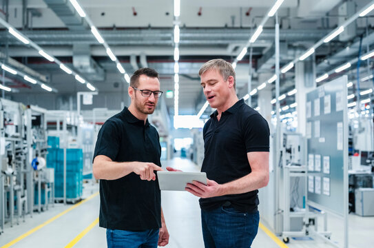 Two colleagues sharing digital tablet in a factory