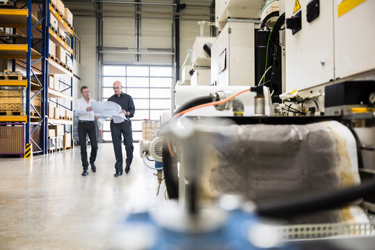 Engineers holding document and having discussion in factory