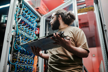Technician looking at cables holding machine part in server room