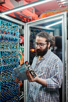IT technician examining machine part in data center