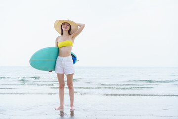 Beautiful slim fit caucasian woman walks on the beach with surfboard. Summer activities and...