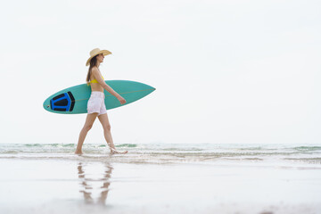 Beautiful slim fit caucasian woman walks on the beach with surfboard. Summer activities and...
