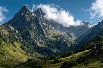 Fototapeta premium Sunlit mountain valley, green slopes, rocky peaks, partly cloudy sky