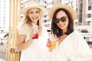 Two young beautiful smiling hipster female in trendy summer white dress and straw hats. Sexy...
