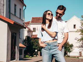 Smiling beautiful woman and her handsome boyfriend. Woman in casual summer jeans clothes. Happy cheerful family. Female having fun. Sexy couple posing in the street at sunny day. In sunglasses